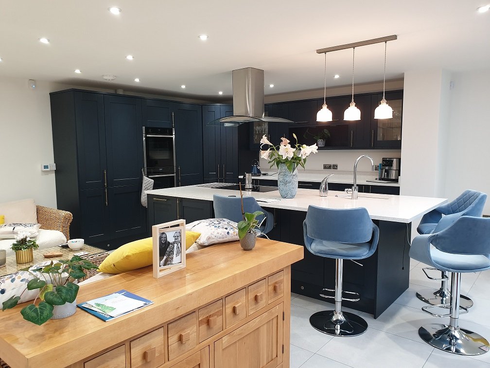 Designing Your Dream Kitchen - Modern Dark Blue Kitchen with a white surface fixed island in the middle with pale blue high stools.